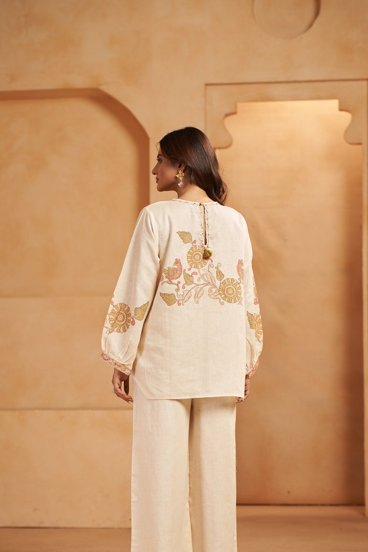 Woman wearing a cream-colored outfit with floral embroidery