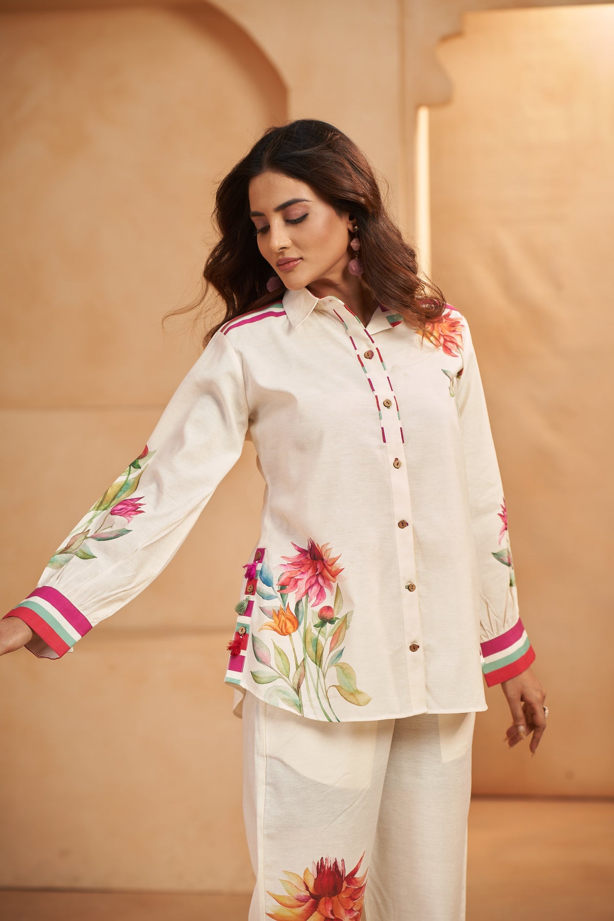 Woman wearing a cream-colored outfit with floral embroidery against a beige background