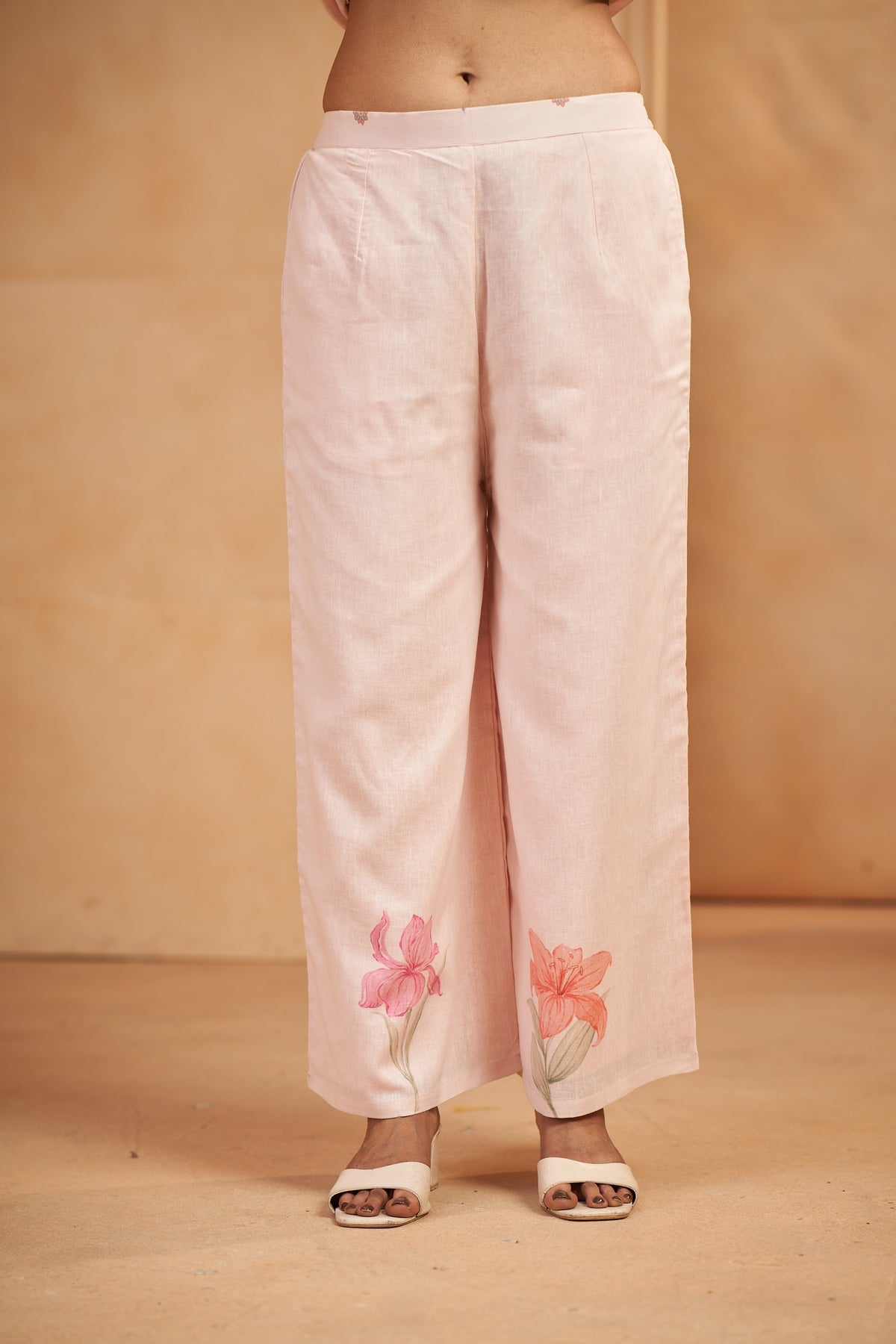 Light pink pants with floral embroidery on a beige background
