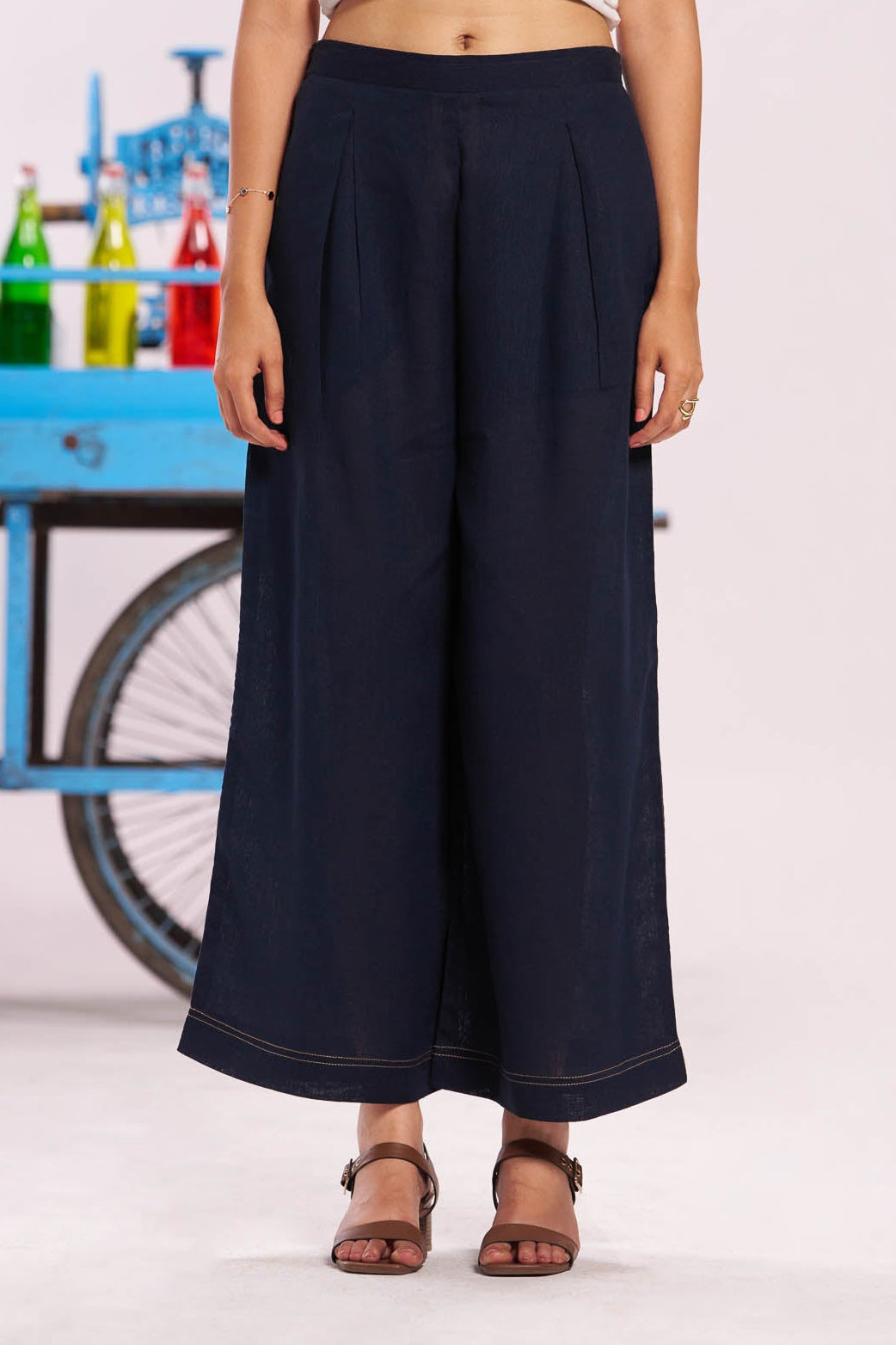 Person wearing navy wide-leg pants with a white top in front of a colorful cart.